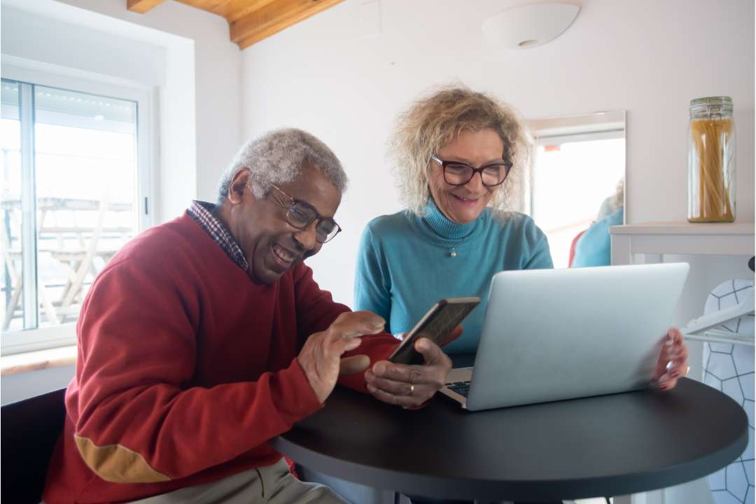 dois idosos sentados na frente de um computador consultando os rendimentos do INSS