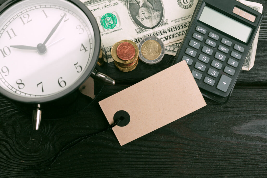 Relógio, calculadora e dinheiro sobre a mesa durante análise sobre investir em previdência privada