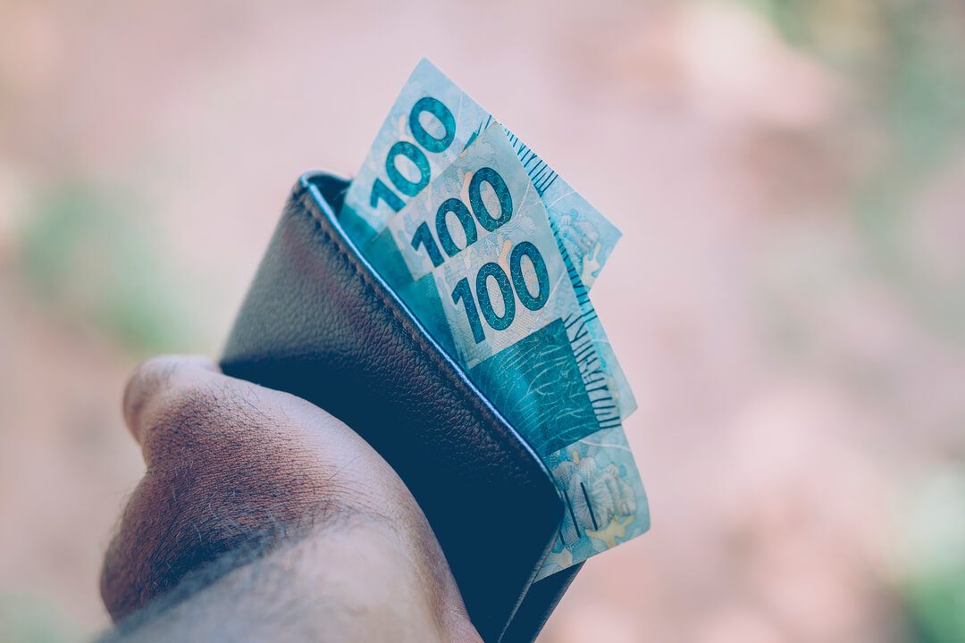 Carteira de investimentos: pessoa segurando uma carteira com notas de dinheiro.