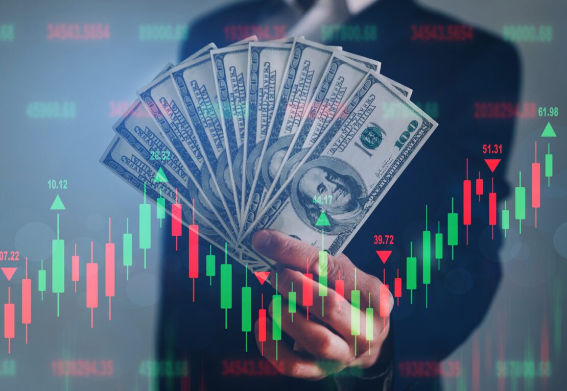 mercado internacional: um homem segurando dólar e um gráfico montando a baixa e a alta da moeda.